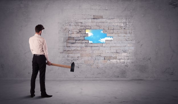 Business man hitting grungy brick wall with hammer