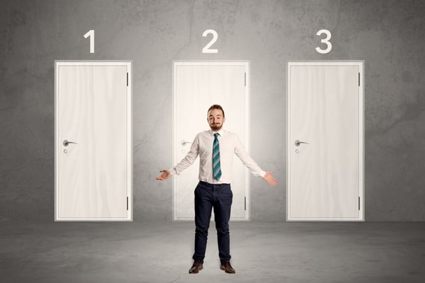 Businessman in grey room with three numbered white  door behind his back-1